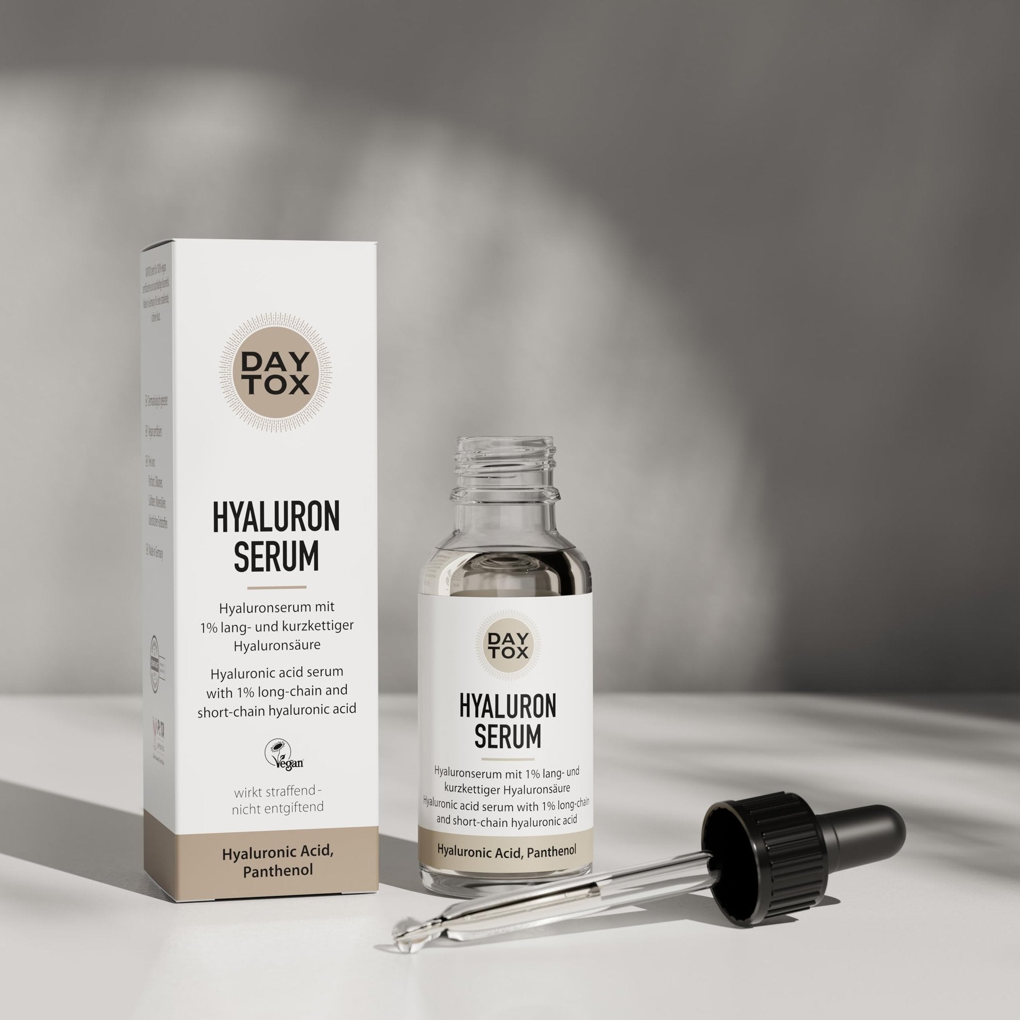 Daytox Hyaluron Serum Flasche mit abgesetzter Pipette und Produktverpackung auf hellem Untergrund.