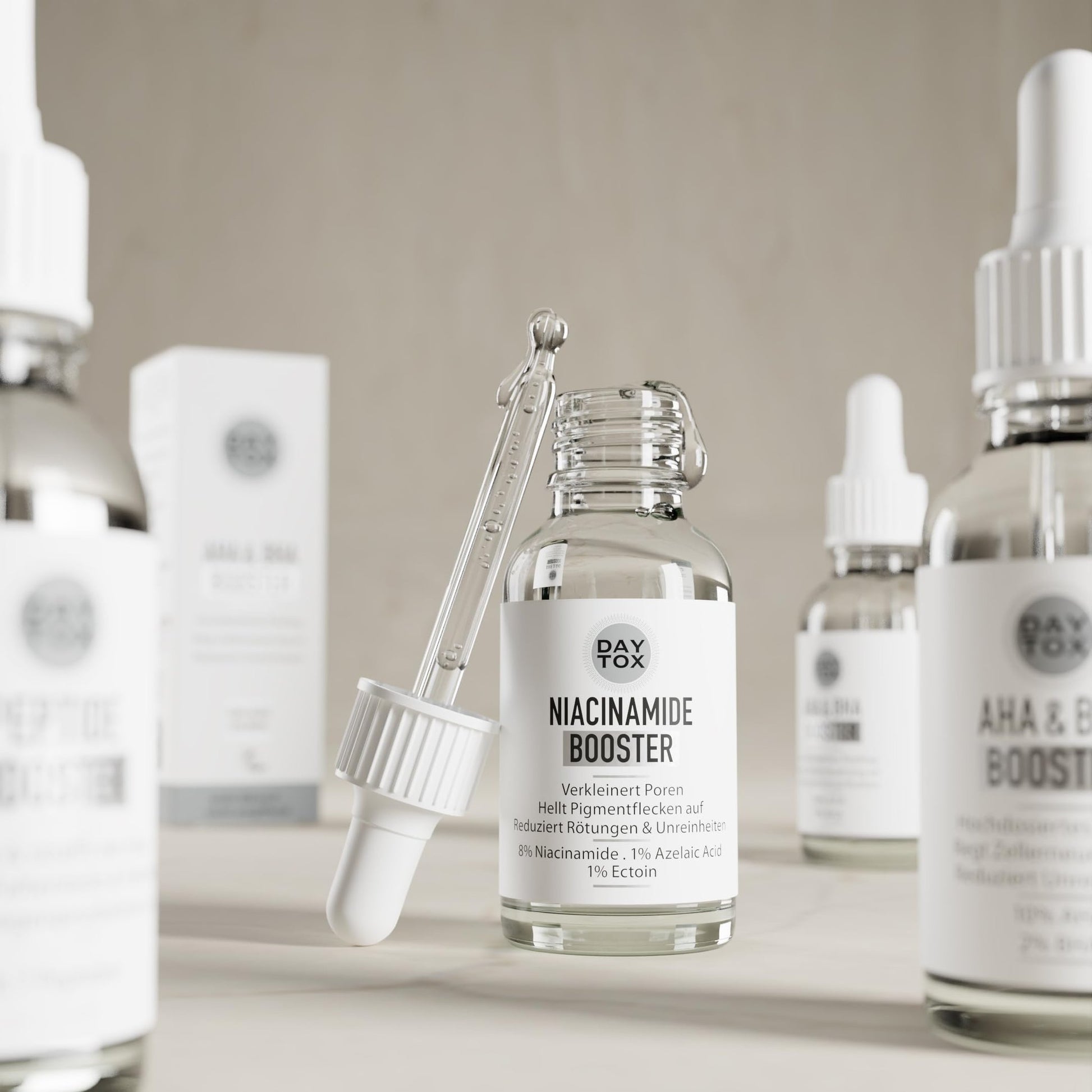 Daytox Niacinamide Booster Flasche mit Pipette in einer Reihe von ähnlichen Produkten auf hellem Tisch.
