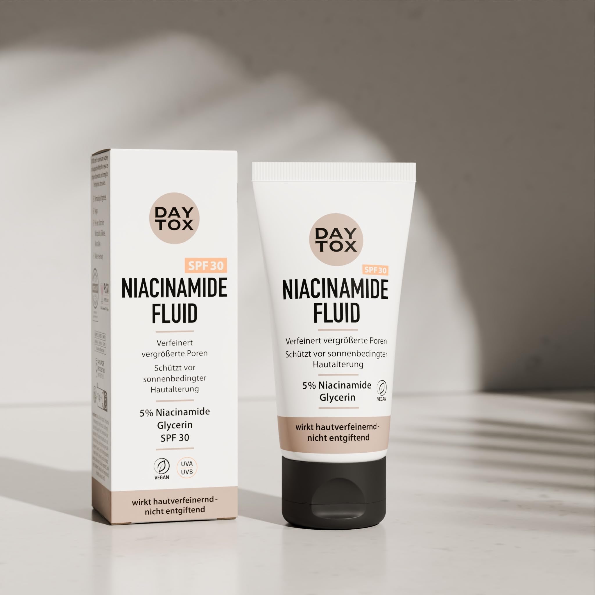 Daytox Niacinamide Fluid Tube und die Vorderseite der Produktverpackung nebeneinander.