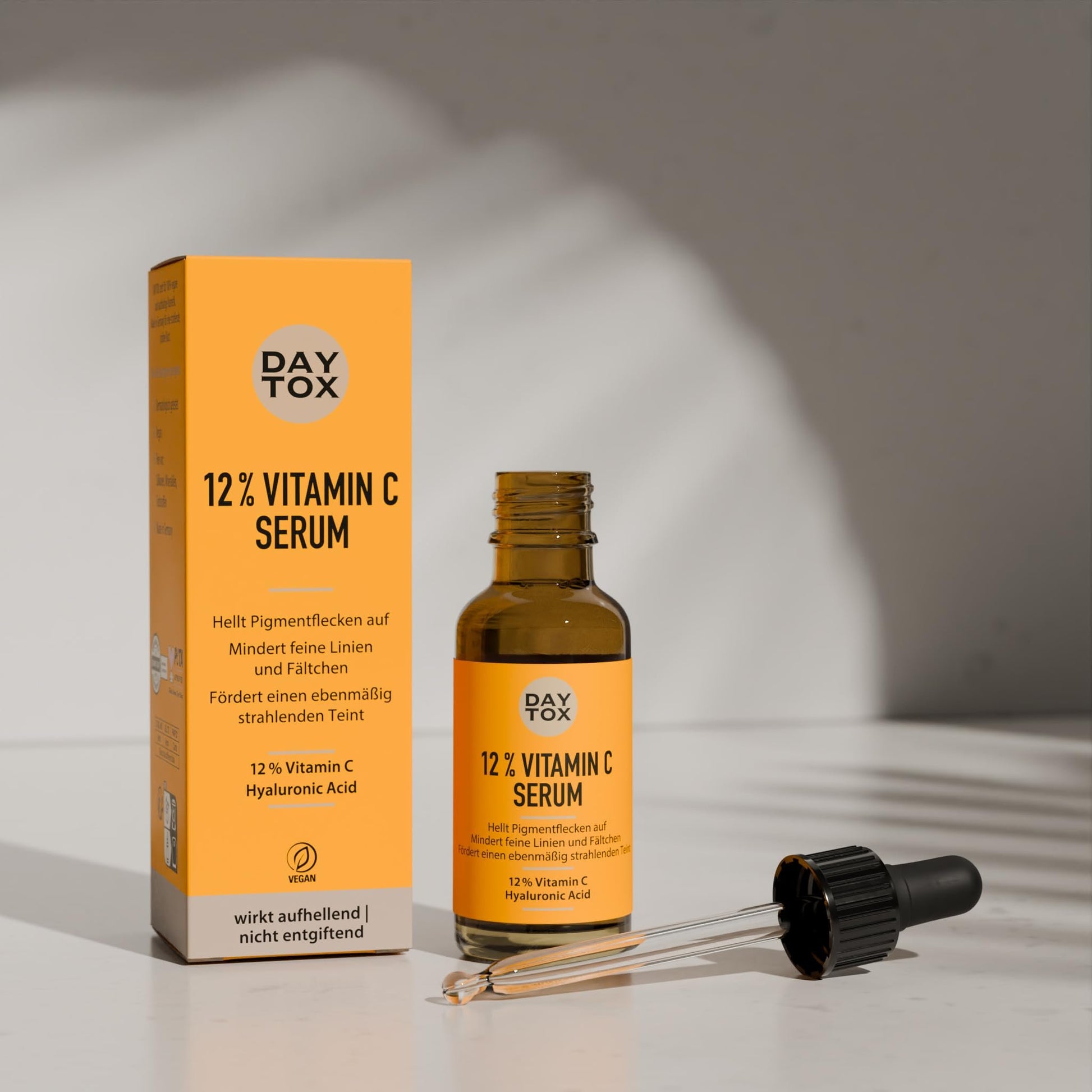 DAYTOX Vitamin C Serum Flasche mit teilweise eingesetzter Pipette und orangefarbene Verpackung.
