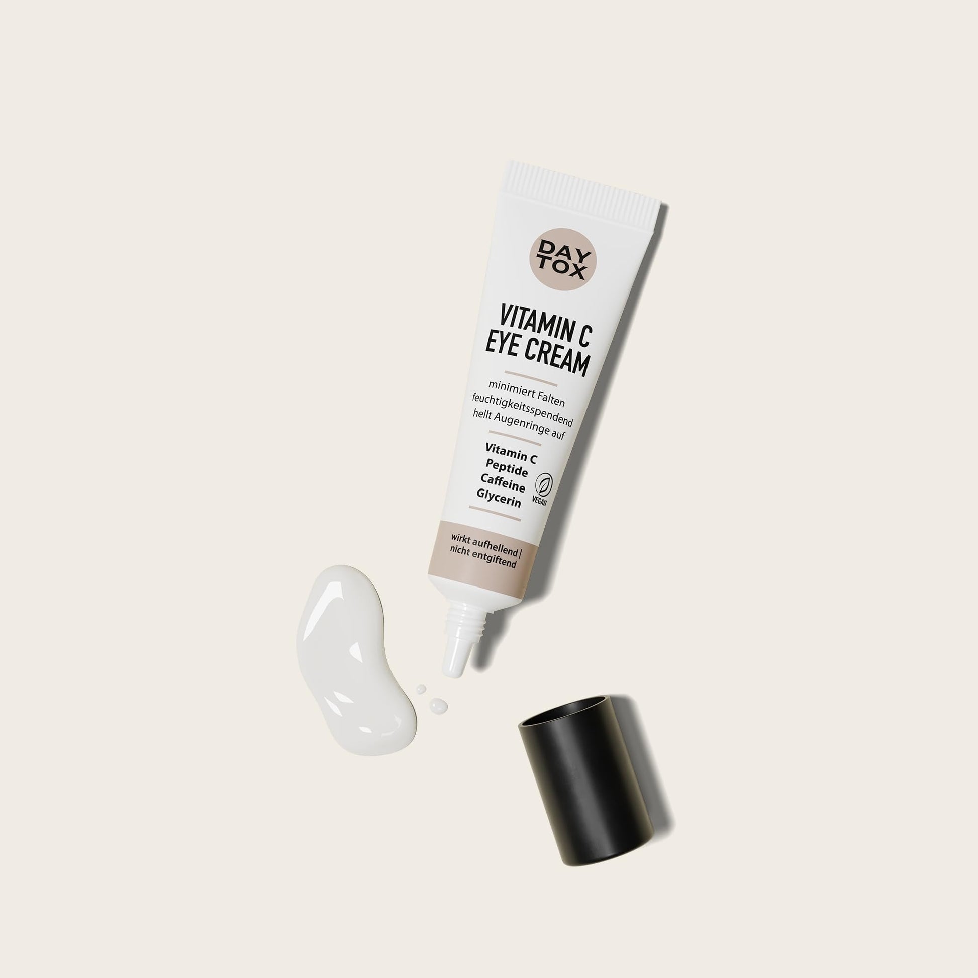 DAYTOX Vitamin C Augencreme Tube mit geöffnetem Deckel und einem Klecks Creme daneben.